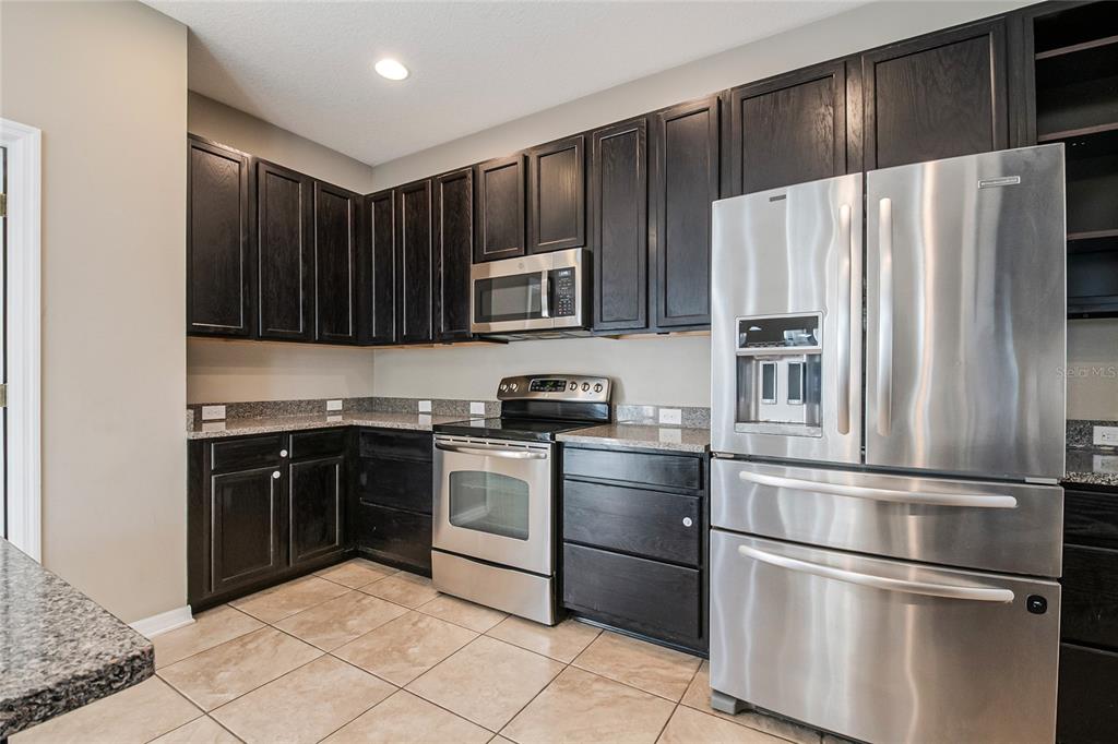 6844 Sundrop Street Harmony, FL 34773 - Photo 21 of 67 a kitchen with stainless steel appliances granite countertop a refrigerator and a stove top oven