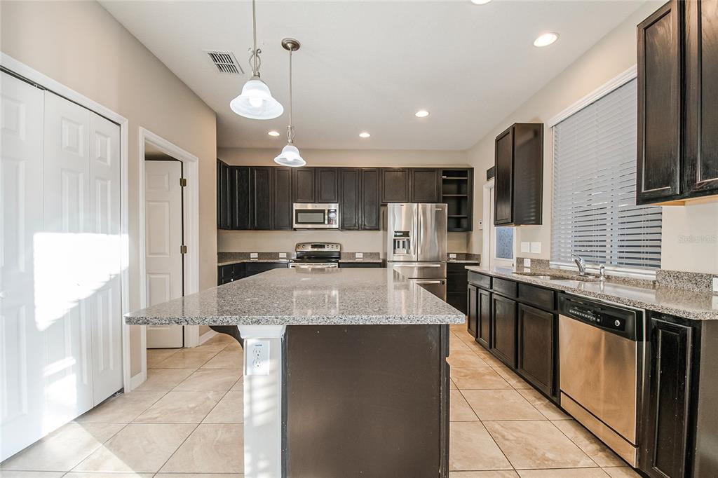 6844 Sundrop Street Harmony, FL 34773 - Photo 23 of 67 a large kitchen with kitchen island a large counter space and stainless steel appliances