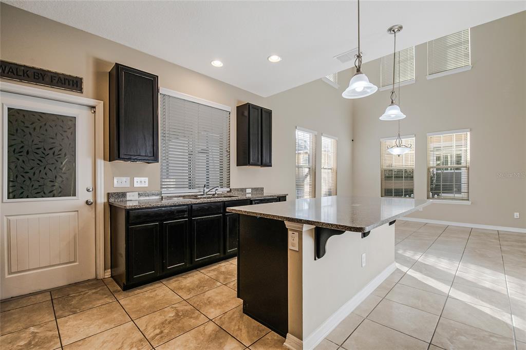 6844 Sundrop Street Harmony, FL 34773 - Photo 24 of 67 a large kitchen with stainless steel appliances kitchen island granite countertop a sink and cabinets