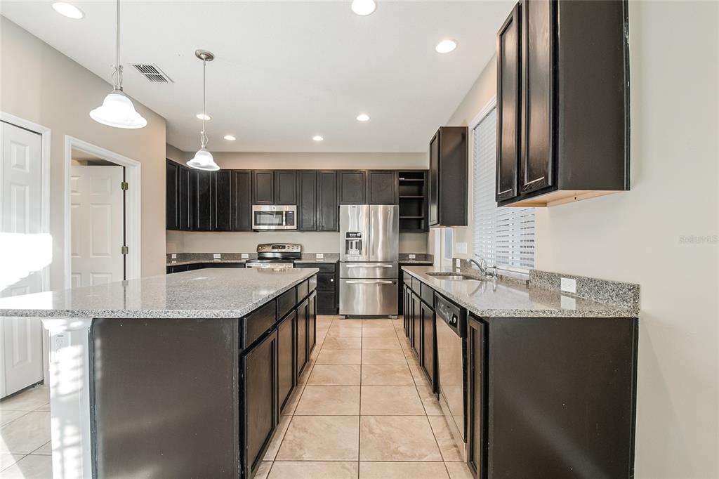 6844 Sundrop Street Harmony, FL 34773 - Photo 25 of 67 a kitchen with stainless steel appliances granite countertop a sink a stove and cabinets