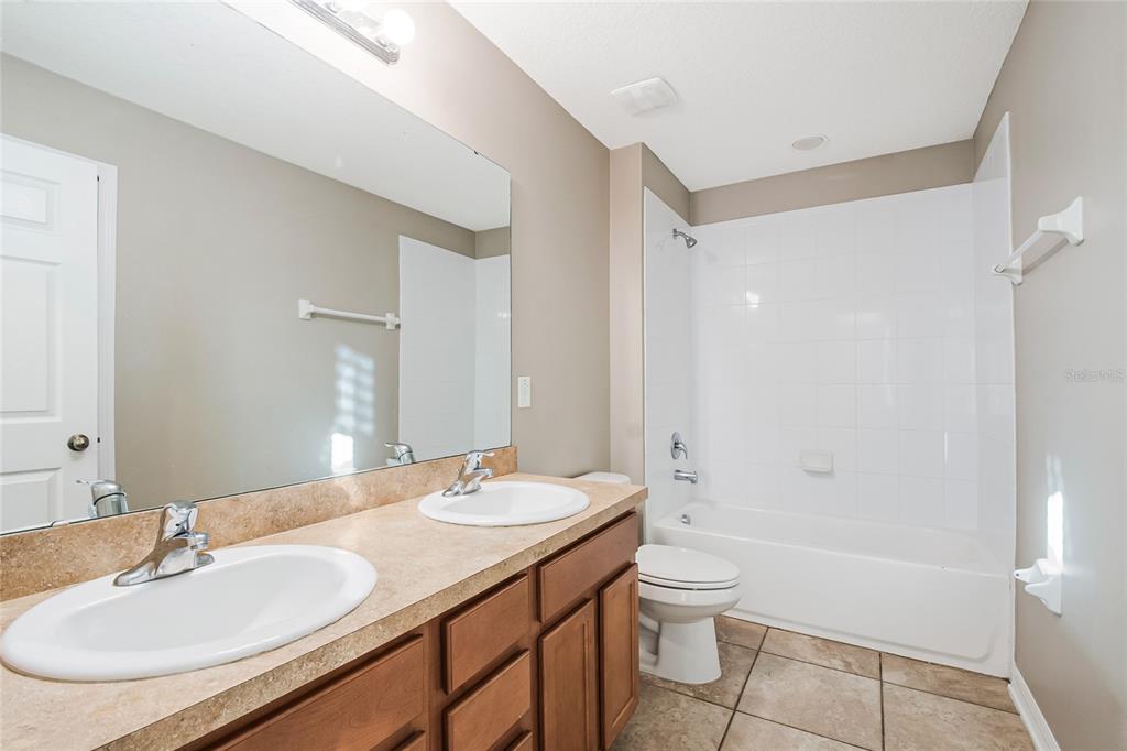 6844 Sundrop Street Harmony, FL 34773 - Photo 42 of 67 a bathroom with a granite countertop sink toilet a shower and a mirror