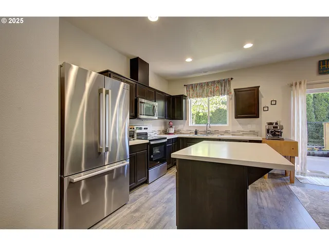 a kitchen with stainless steel appliances granite countertop a refrigerator a sink dishwasher a stove with wooden cabinets