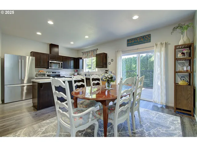 a dining room with stainless steel appliances granite countertop a table chairs and a refrigerator