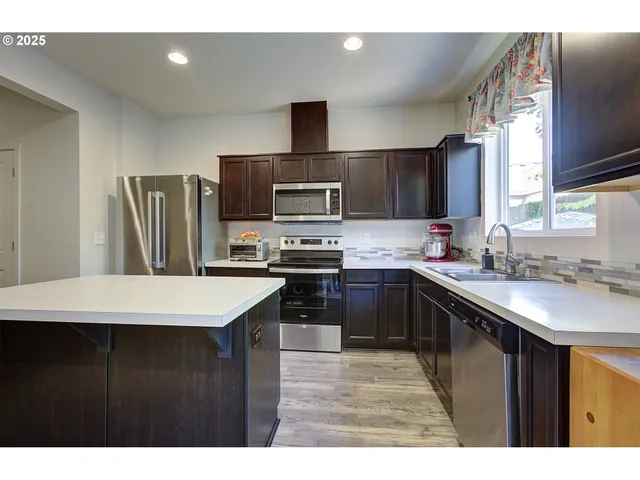 a kitchen with stainless steel appliances a refrigerator a sink a stove a microwave a center island and a refrigerator