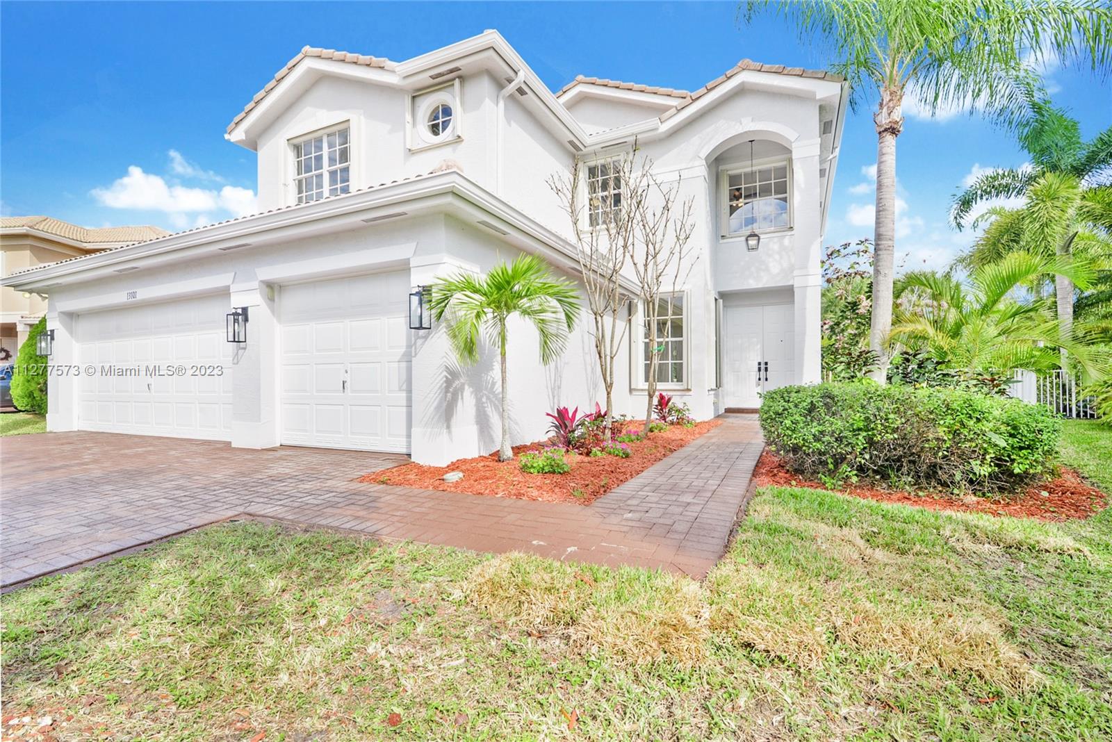 a view of a white house with a small yard and plants