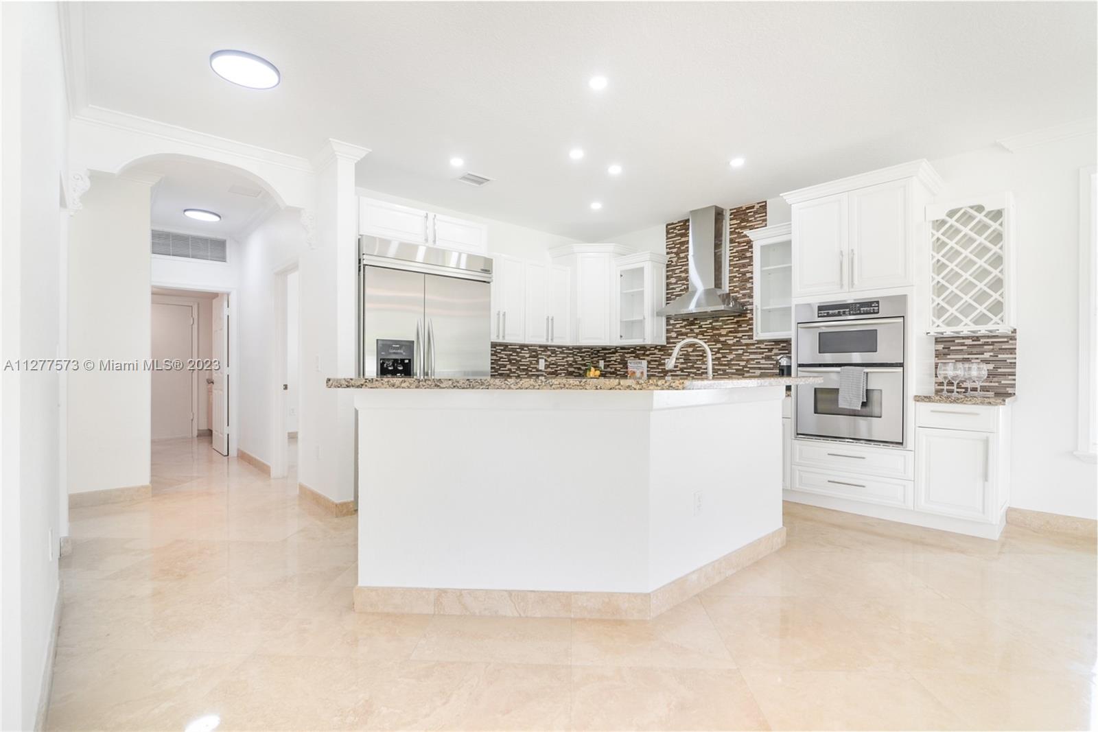 Silver Falls Miramar, FL 33027 - Photo 8 of 46 a large white kitchen with kitchen island a stove a sink a refrigerator and white cabinets