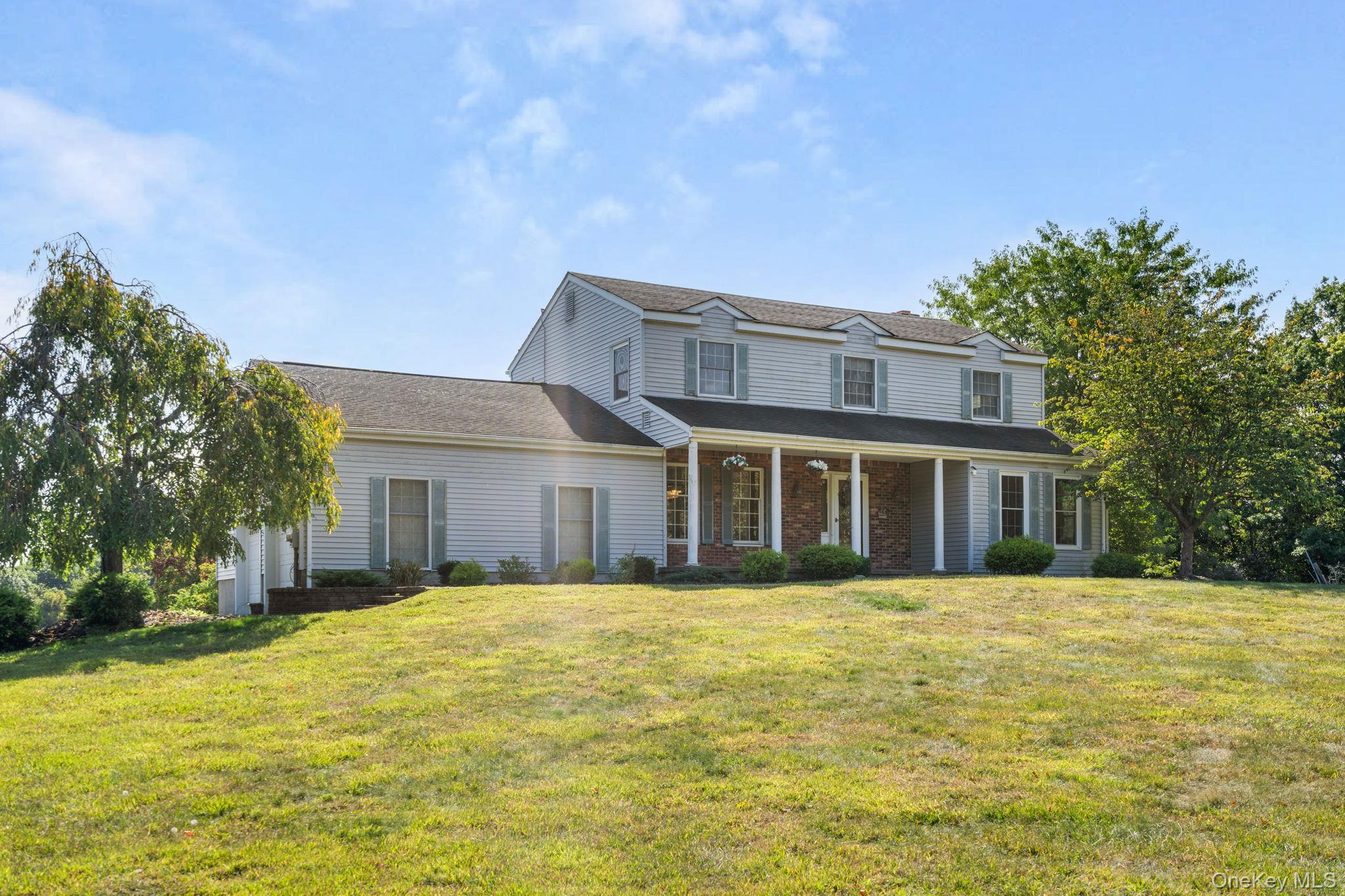 Traditional-style home with a front lawn, covered porch, and brick siding