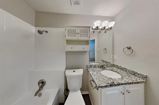 a bathroom with a granite countertop sink a toilet and a mirror