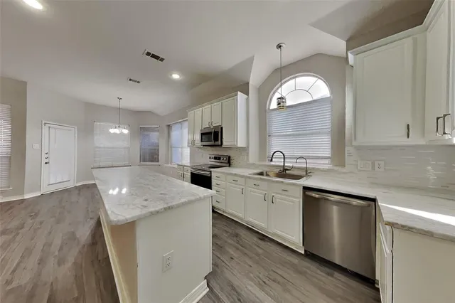 a kitchen with stainless steel appliances granite countertop a sink stove and wooden floor