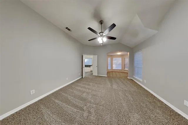 an empty room with a ceiling fan and window