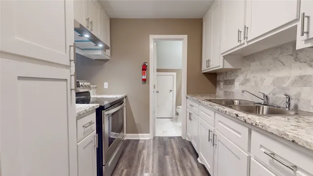 a kitchen with granite countertop a sink stove and refrigerator