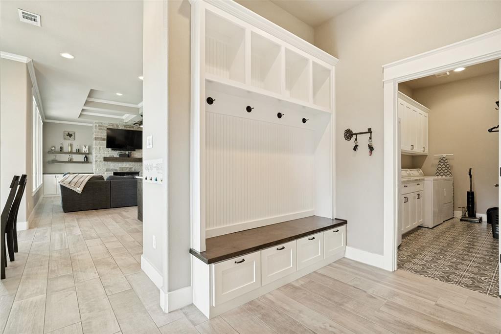 6913 Veal Station Road Weatherford, TX 76085 - Photo 23 of 31 Built-in white cabinetry with a dark wood-finish benchtop, beadboard backing, storage cubbies, and coat hooks