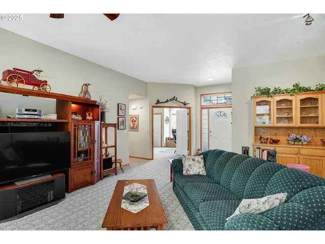 a living room with furniture a flat screen tv and a refrigerator