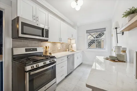 a kitchen with stainless steel appliances white cabinets and a stove top oven