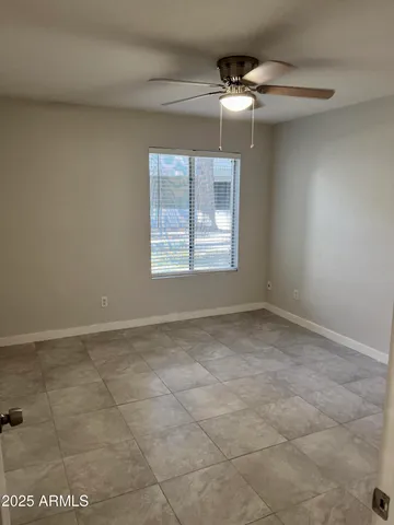 an empty room with a chandelier fan and windows