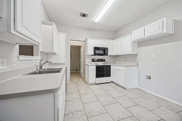 a kitchen with a sink a stove top oven and cabinets