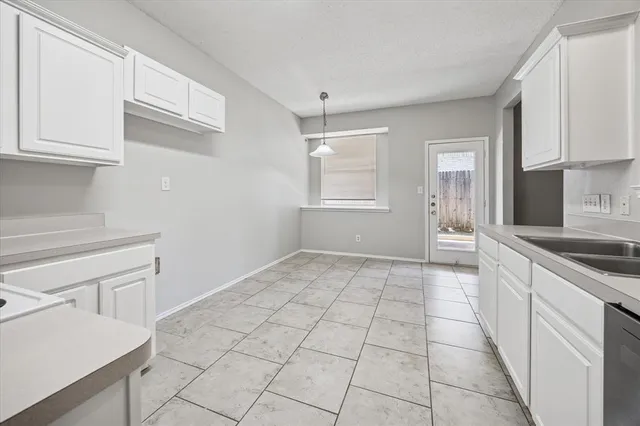 a kitchen with white cabinets appliances and a window