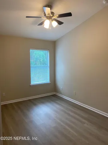 an empty room with a window and a fan