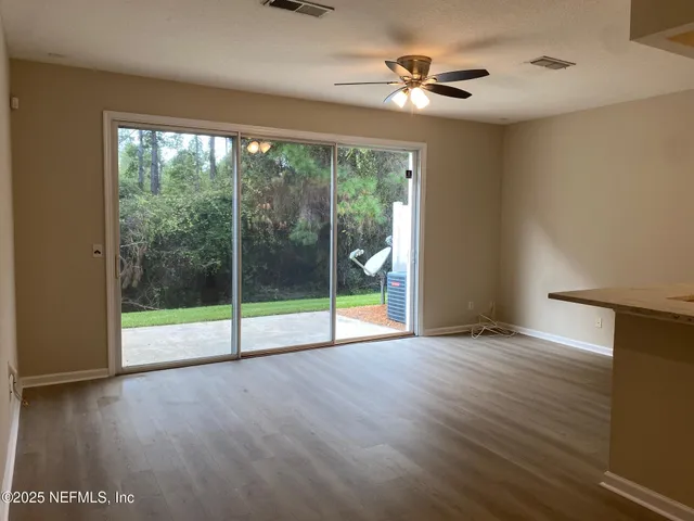 a view of an empty room with wooden floor and a ceiling fan