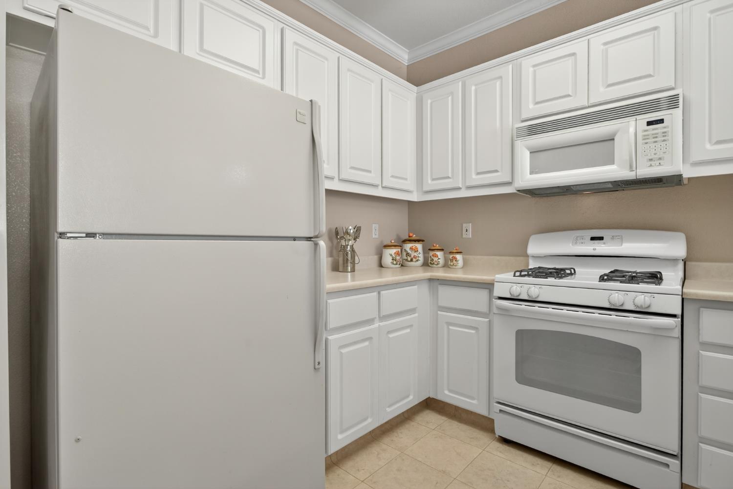 3200 Spring Garden Drive Turlock, CA 95382 - Photo 10 of 30 a white refrigerator freezer and a stove sitting inside of white cabinets