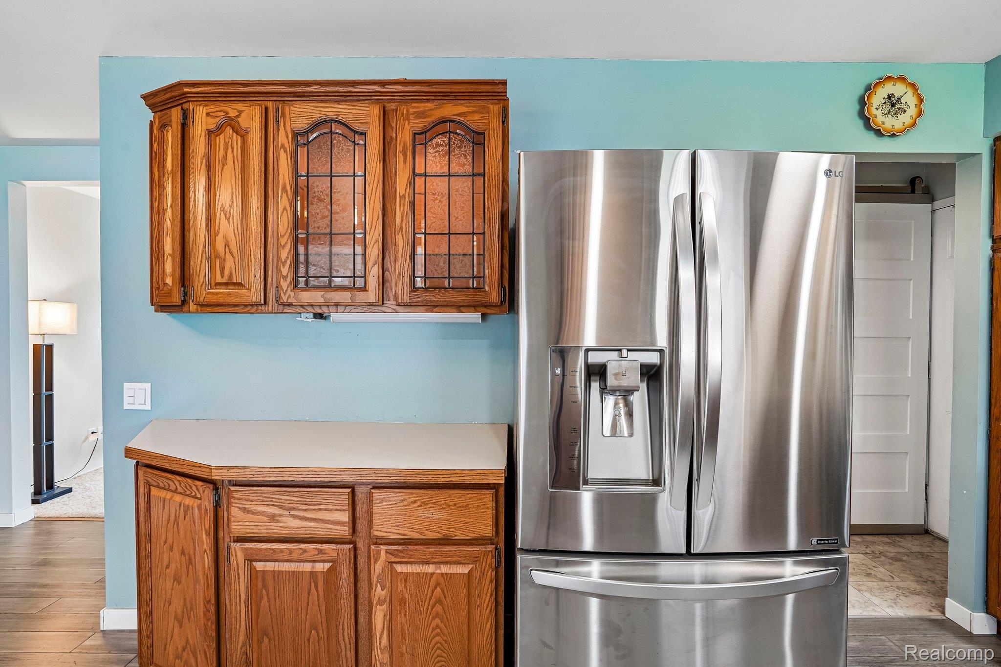3981 South State Road Durand, MI 48429 - Photo 9 of 33 Stainless steel French door refrigerator with ice and water dispenser, wood cabinetry with leaded glass accents, and a light-toned countertop