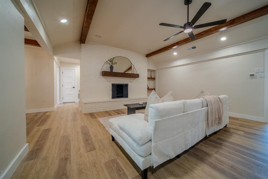 5125 Ashbrook Road Dallas, TX 75227 - Photo 9 of 34 Wood-finish flooring throughout, featuring a white brick fireplace with a wood mantel