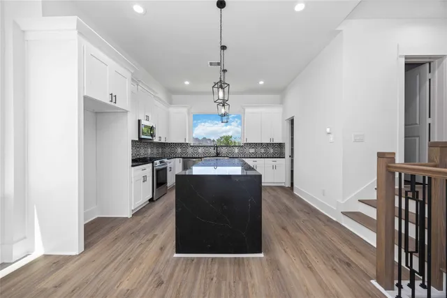 a kitchen with kitchen island stainless steel appliances a dining table chairs and wooden floor