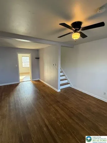 a view of empty room with wooden floor and fan