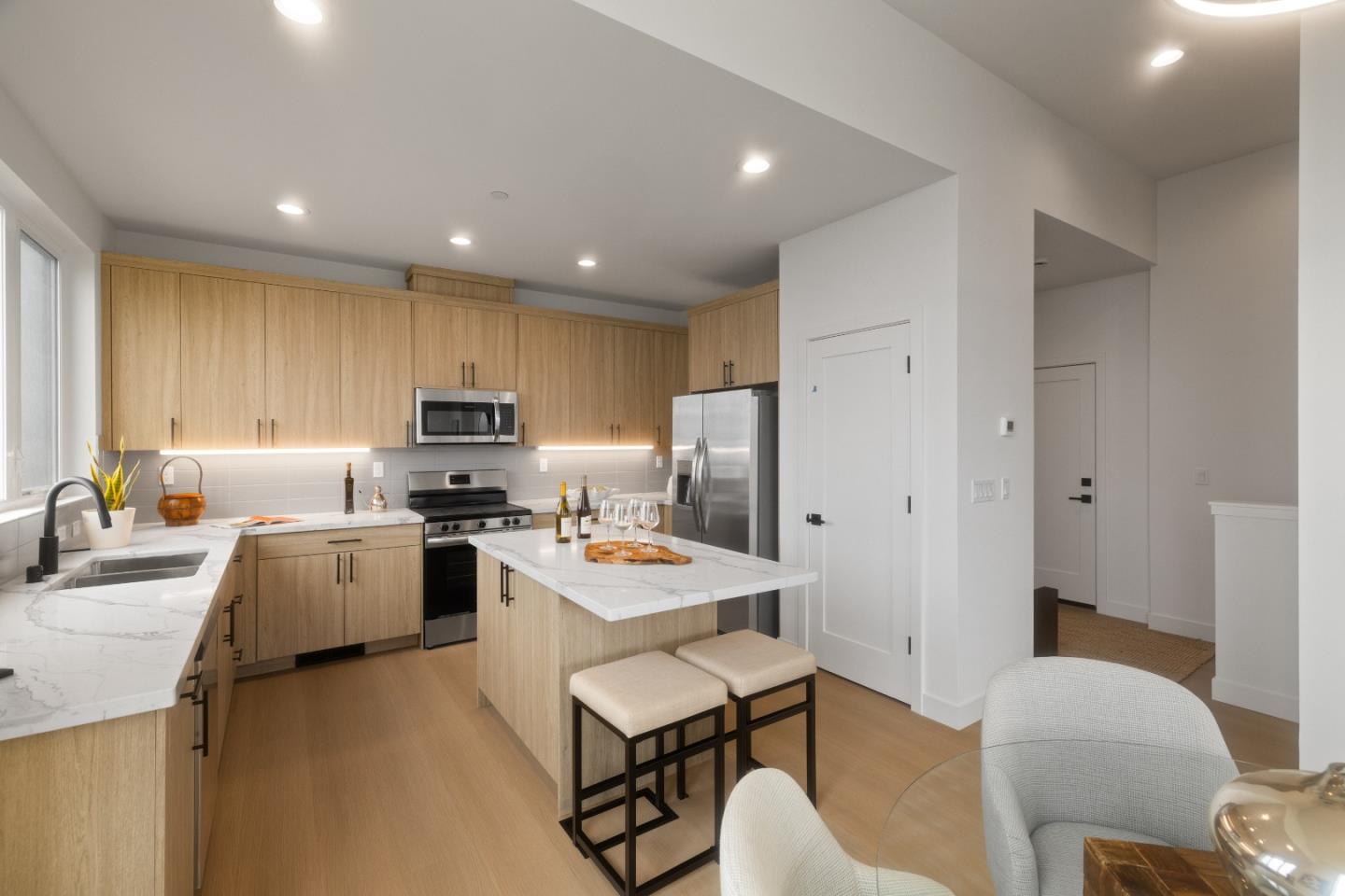 a kitchen with a refrigerator a stove a sink dishwasher a dining table and chairs with wooden floor