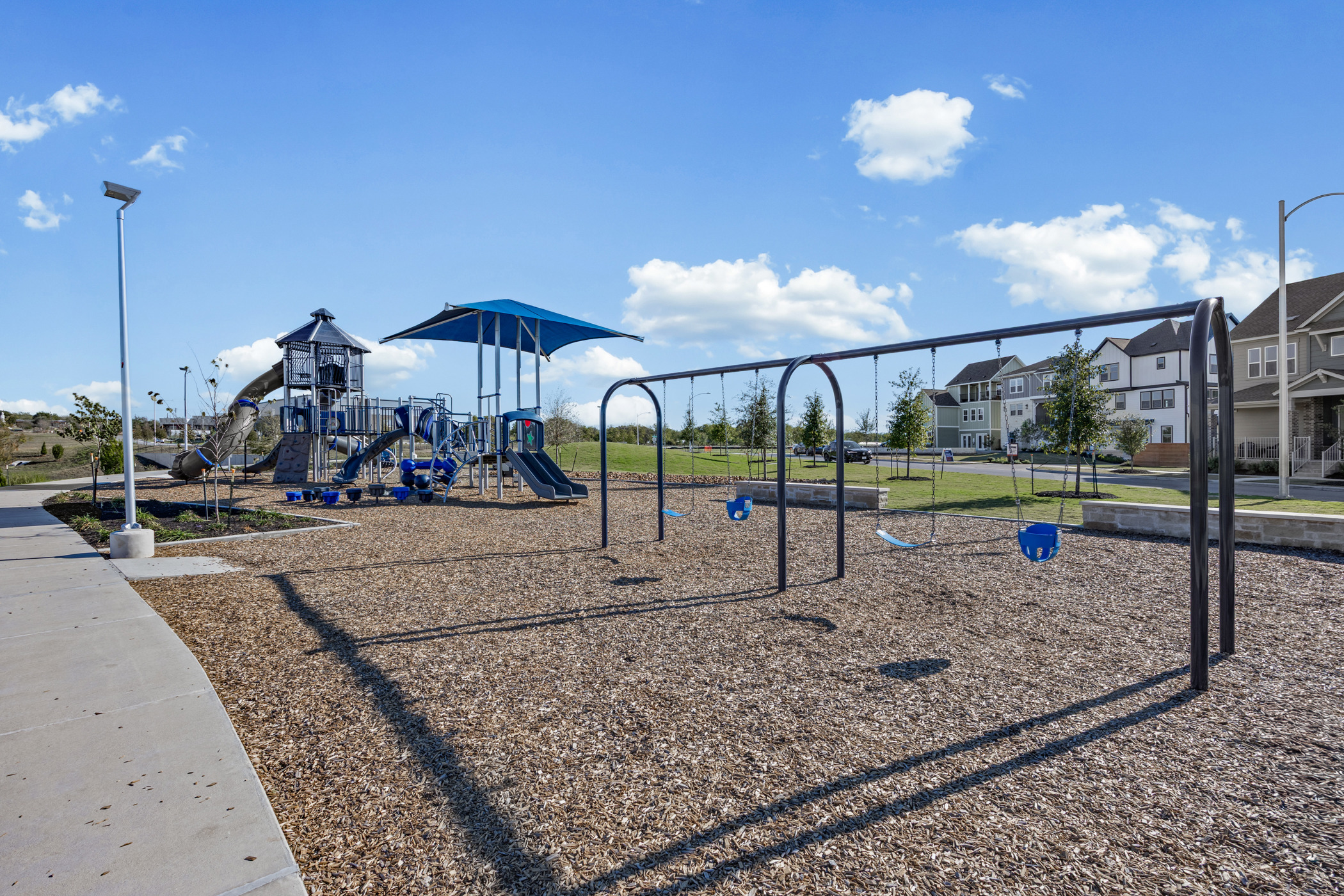 5806 Rangeland Road Austin, TX 78747 - Photo 32 of 34 A community playground, complete with slides and swings, offers outdoor recreation amidst residential architecture.