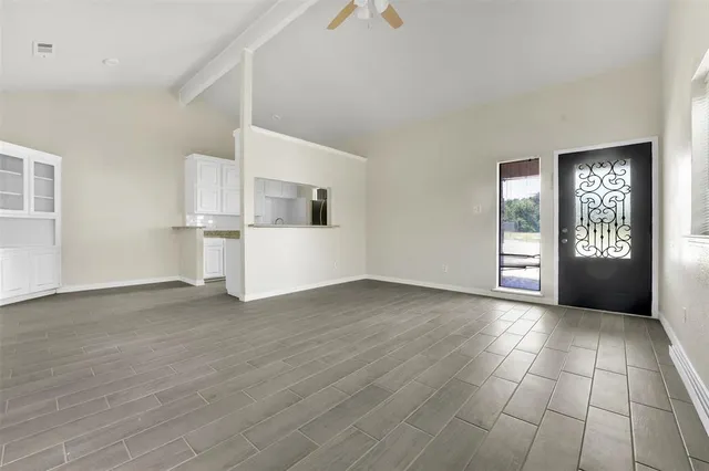 a view of an empty room with a window and wooden floor