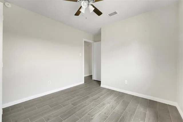 an empty room with a ceiling fan and wooden floor