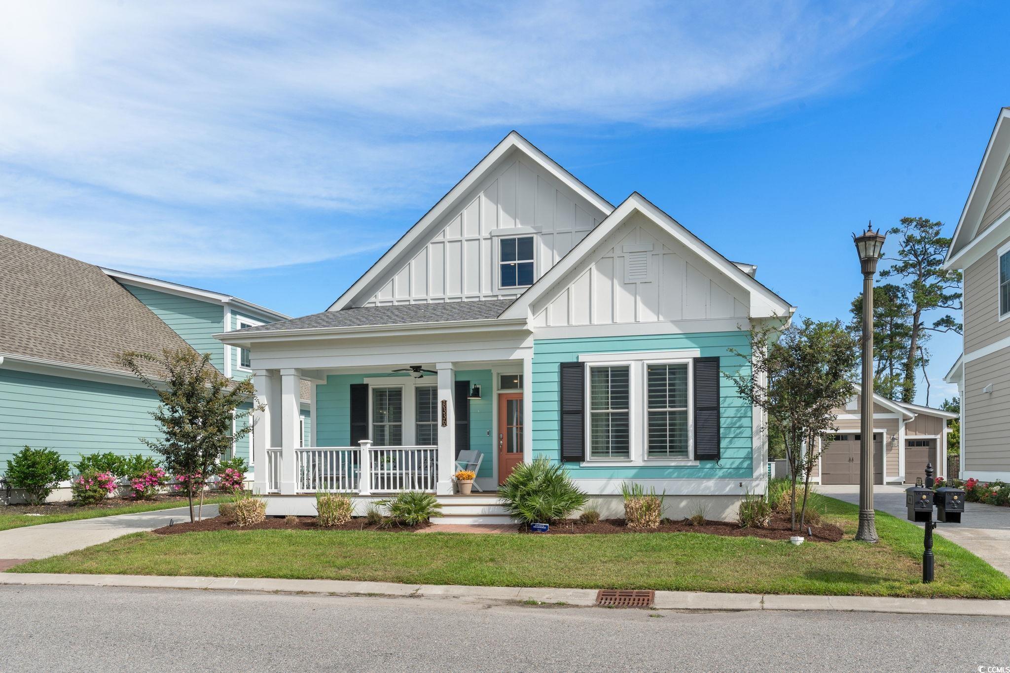 View of front of home with board and batten siding, covered porch, a front yard, a garage, and ceiling fan
