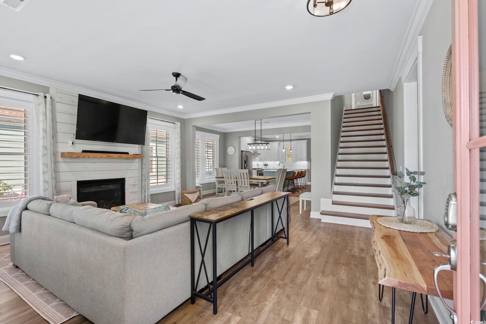 8336 Sandlapper Way Myrtle Beach, SC 29572 - Photo 8 of 40 Living room with ornamental molding, ceiling fan, stairs, wood finished floors, and a large fireplace