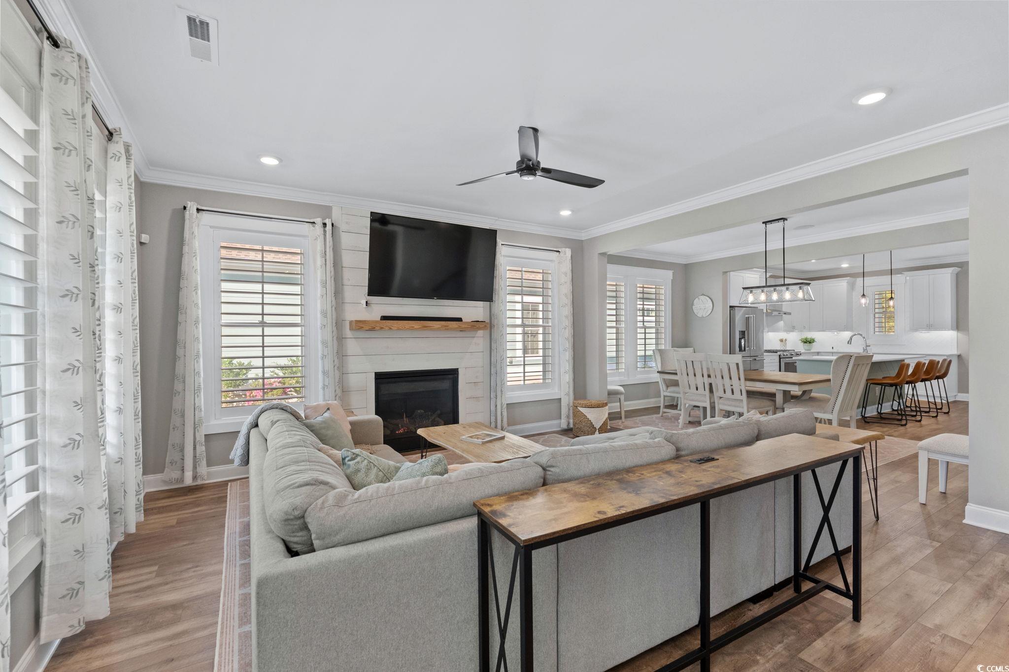 8336 Sandlapper Way Myrtle Beach, SC 29572 - Photo 9 of 40 Living area featuring plenty of natural light, crown molding, a ceiling fan, light wood finished floors, and a fireplace