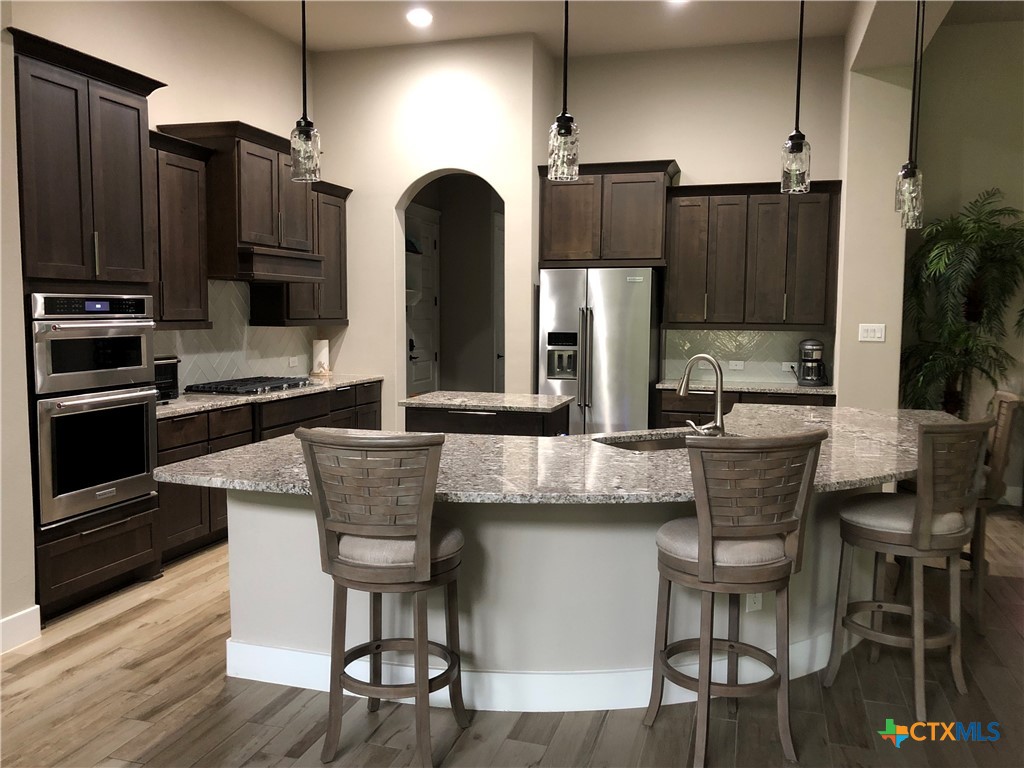 407 Havasu Point Spring Branch, TX 78070 - Photo 34 of 36 a kitchen with stainless steel appliances granite countertop a table chairs stove and refrigerator