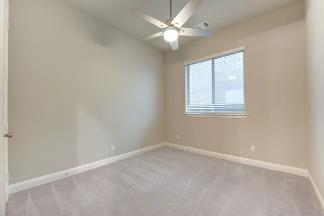 an empty room with a chandelier fan and windows