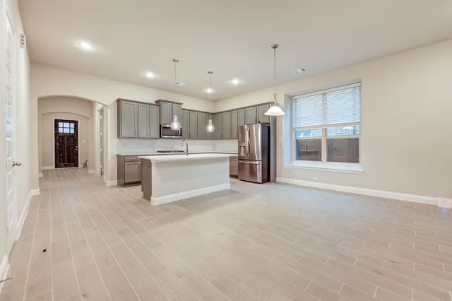 a kitchen with stainless steel appliances granite countertop a refrigerator oven a sink dishwasher and white cabinets with wooden floor