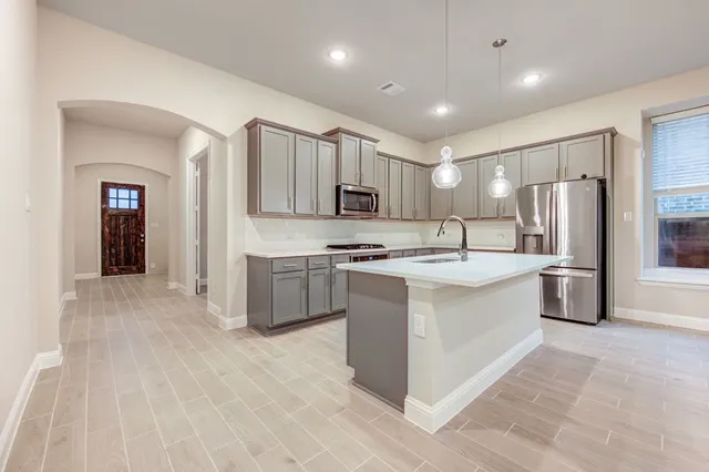 a large kitchen with stainless steel appliances granite countertop a large counter top a sink and a stove