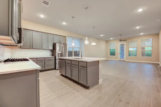 a kitchen with stainless steel appliances granite countertop a kitchen island a stove a sink and a refrigerator