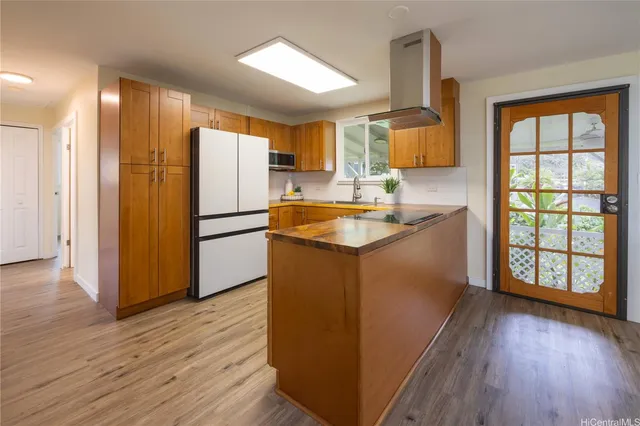 a kitchen with kitchen island granite countertop wooden floors and wide window