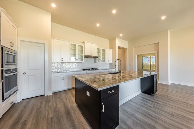a large kitchen with stainless steel appliances kitchen island granite countertop a large counter top and wooden floors