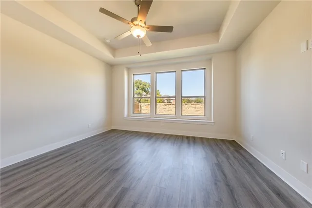 an empty room with wooden floor and ceiling fan
