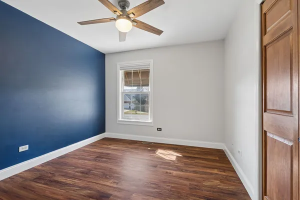 an empty room with wooden floor fan and windows