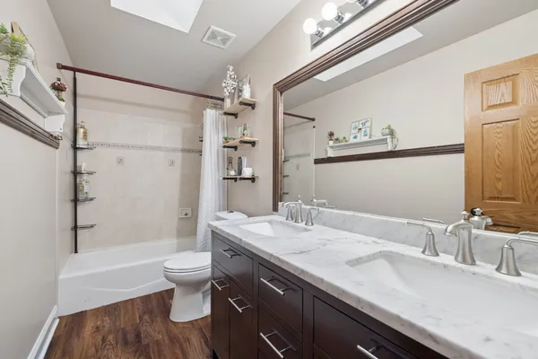 a bathroom with a granite countertop sink a toilet a mirror and shower