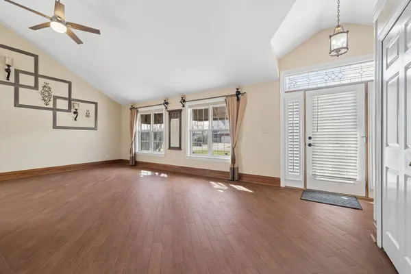 an empty room with wooden floor and windows