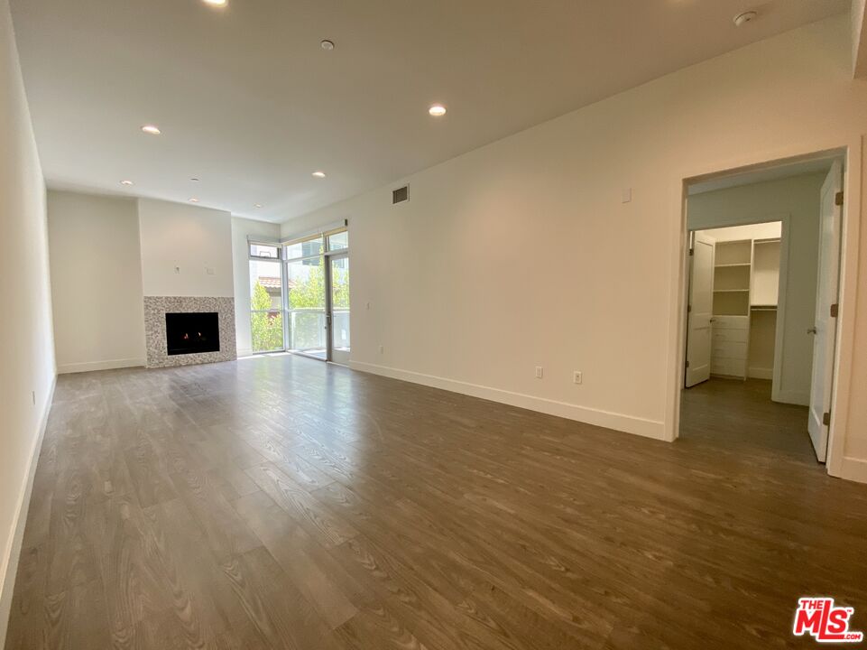 1232 North Kings Road, Unit 105 West Hollywood, CA 90069 - Photo 5 of 22 an empty room with wooden floor and fireplace