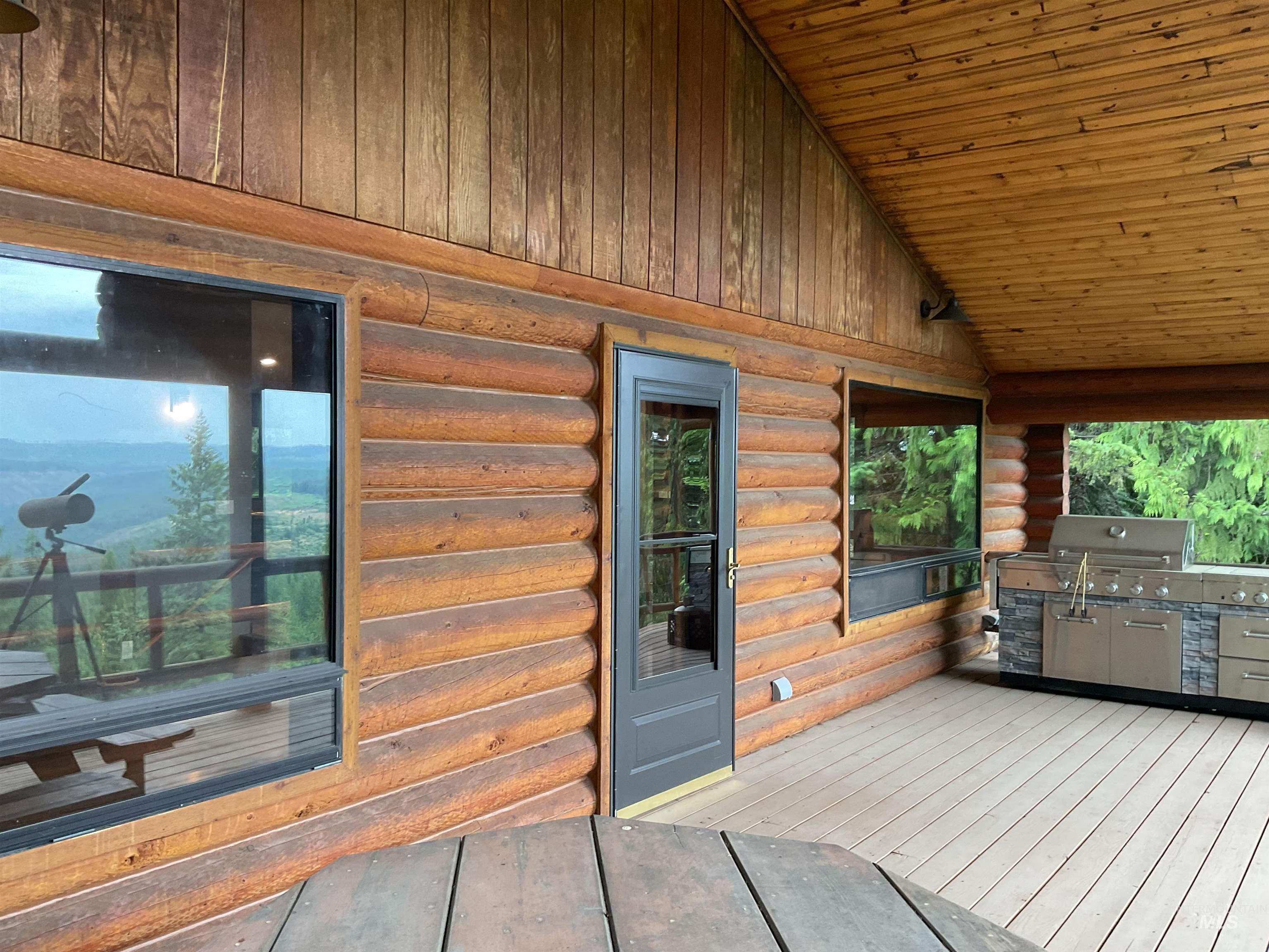 6125 Freeman Creek Road Lenore, ID 83541 - Photo 24 of 44 Expansive outdoor deck featuring log cabin construction, natural wood ceiling, wood-finish flooring, a large horizontal window, and a dark-framed glass door