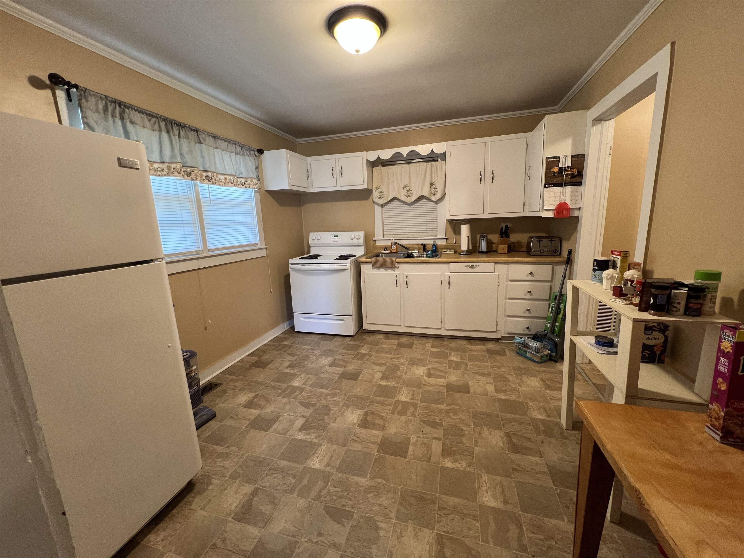 323 North Maple Street Adamsville, TN 38310 - Photo 8 of 16 Kitchen featuring dark tile patterned floors, white cabinets, crown molding, and white appliances