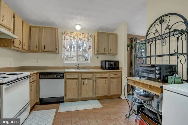 a kitchen with stainless steel appliances granite countertop a stove top oven a sink a dining table and chairs